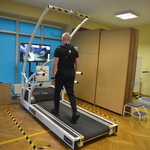 Sala rehabilitacyjna, mężczyzna idący na bieżni mechanicznej